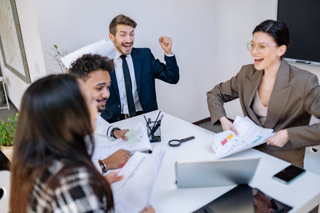 A group of diverse coworkers in a modern office celebrate a successful business meeting with smiles and enthusiasm.