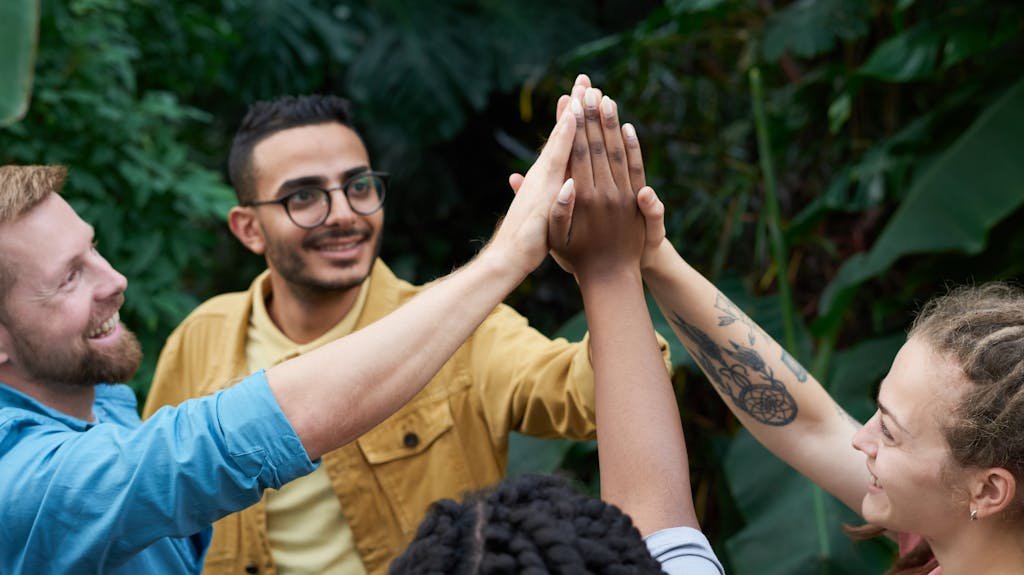 A joyful group of friends high-fiving outdoors, symbolizing teamwork and camaraderie.